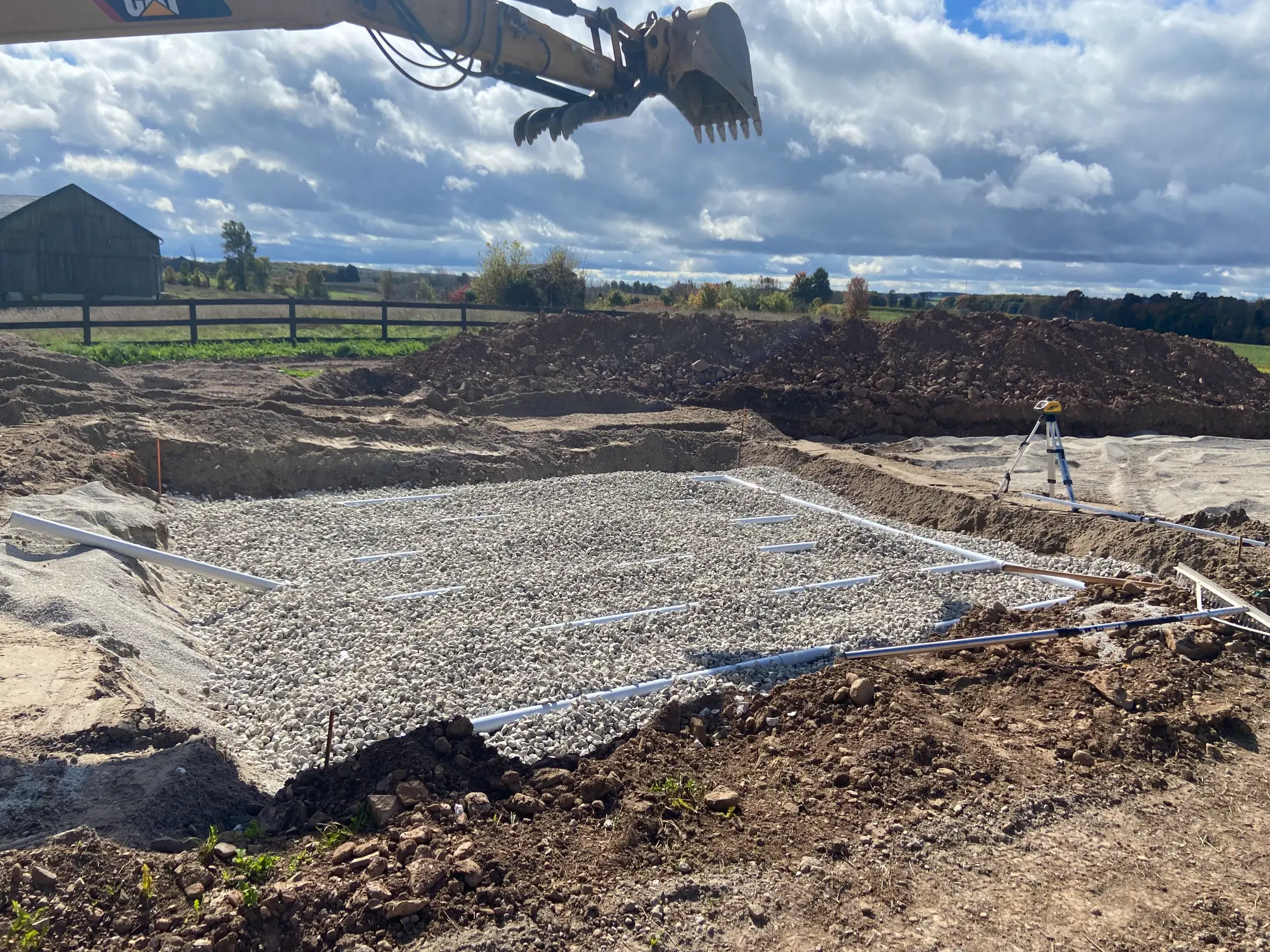 Septic system installation with gravel and weeping tile pipes laid for a new bed.